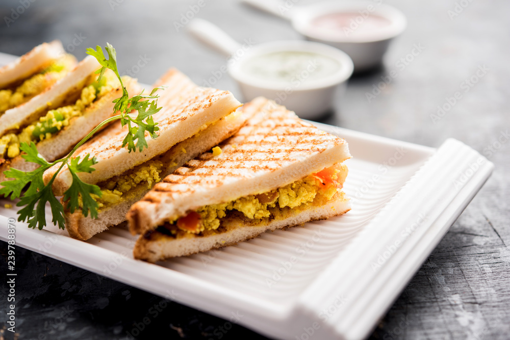 Paneer bhurji sandwich is a tasty paneer based dish made with cottage cheese.served with fresh tomato ketchup and green mint chutney. selective focus Paneer bhurji sandwich is a tasty paneer based dish made with cottage cheese.served with fresh tomato ketchup and green mint chutney. selective focus