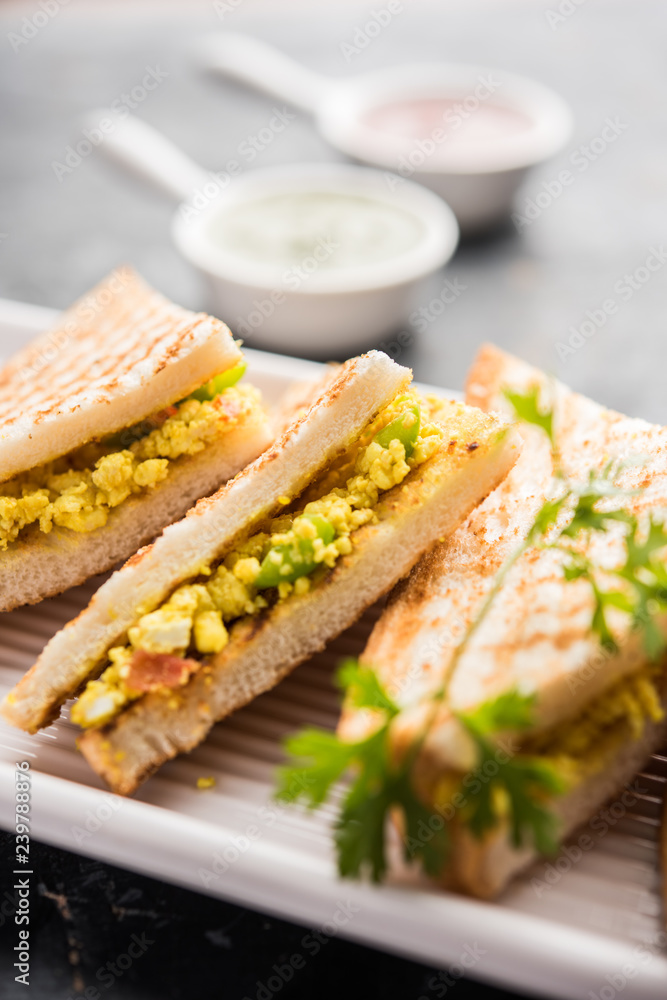 Paneer bhurji sandwich is a tasty paneer based dish made with cottage cheese.served with fresh tomato ketchup and green mint chutney. selective focus Paneer bhurji sandwich is a tasty paneer based dish made with cottage cheese.served with fresh tomato ketchup and green mint chutney. selective focus