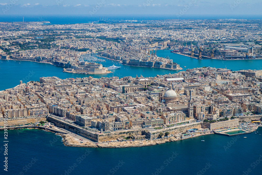 Fototapeta premium Malta aerial view. Valetta, capital city of Malta, Grand Harbour, Senglea and Il-Birgu (Vittoriosa) towns, Fort Ricasoli and Fort Saint Elmo from above. Marsaxlokk city and Freeport in background