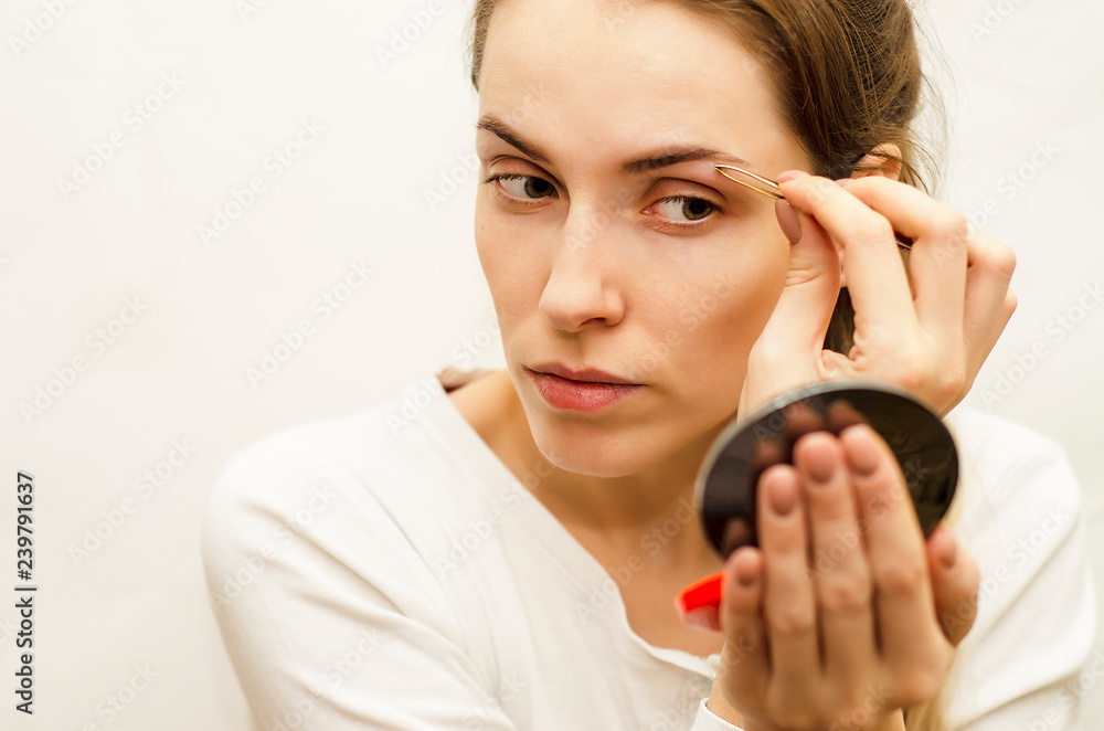 girl in a white jacket makes a day makeup natural cosmetics, on a white background girl in a white jacket makes a day makeup natural cosmetics, on a white background