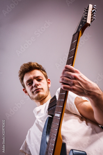 Young man is playing electric guitar