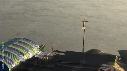 It's dusk and the Mekong flows fast. The material roofs of traders stalls blow in the wind and smoke from their fires swirl.