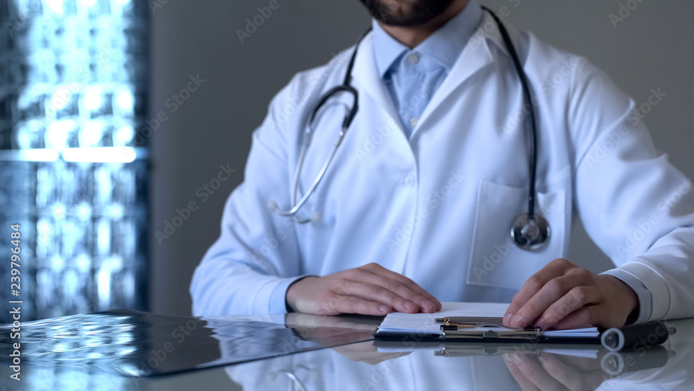 Experienced traumatologist working in medical clinic and examining x-ray plates