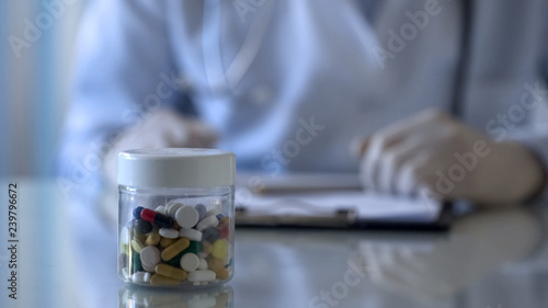 Doctor prescribing medication and giving jar with tablets  hands close-up