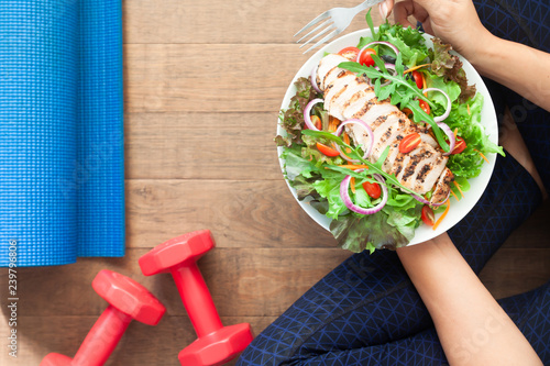 Healthy lifestyle concept. Top view sporty woman eating salad dish