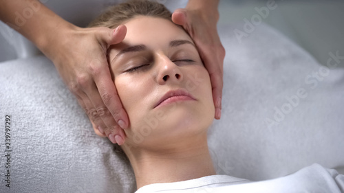 Cosmetologist moisturizing clients skin, massaging face skin, anti-age effect