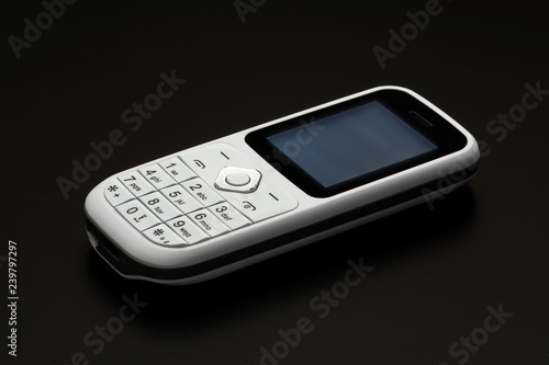 White push-button mobile phone of the old model on a black background