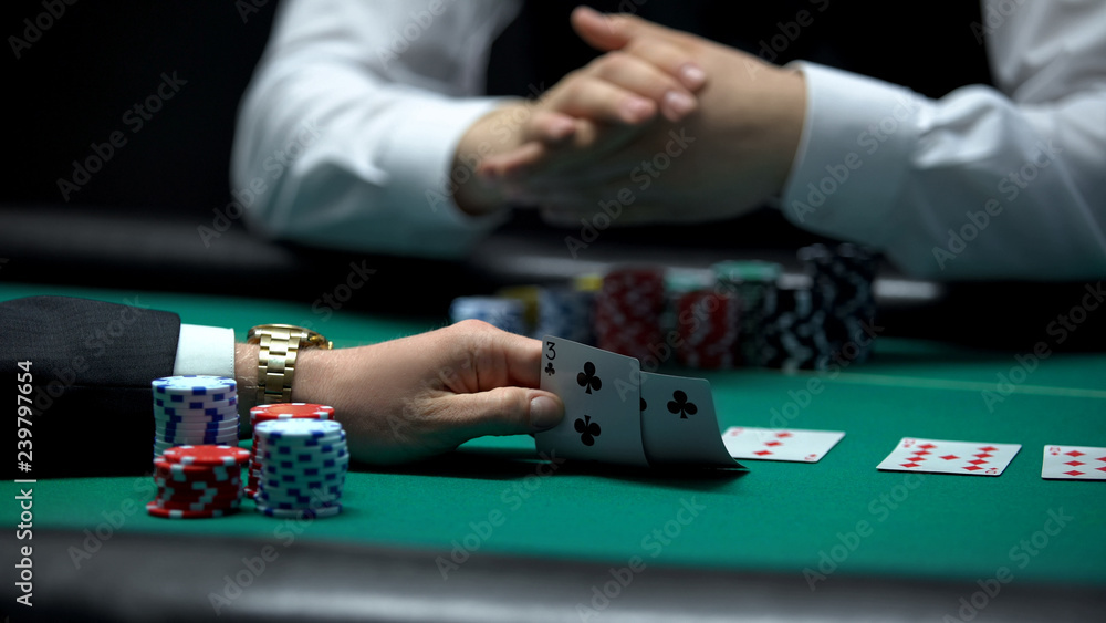 Poker player checking bad combination of cards dealt by croupier, weak hand Poker player checking bad combination of cards dealt by croupier, weak hand