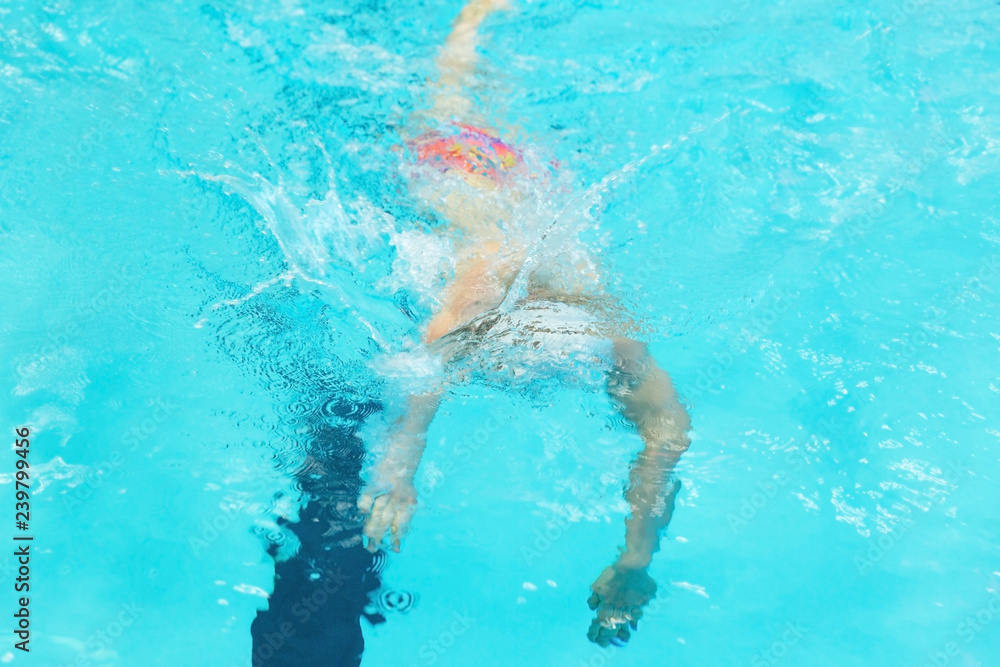 Young man swimming under water in sport pool