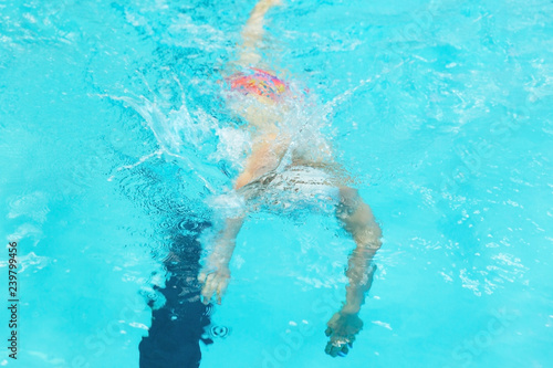 Young man swimming under water in sport pool