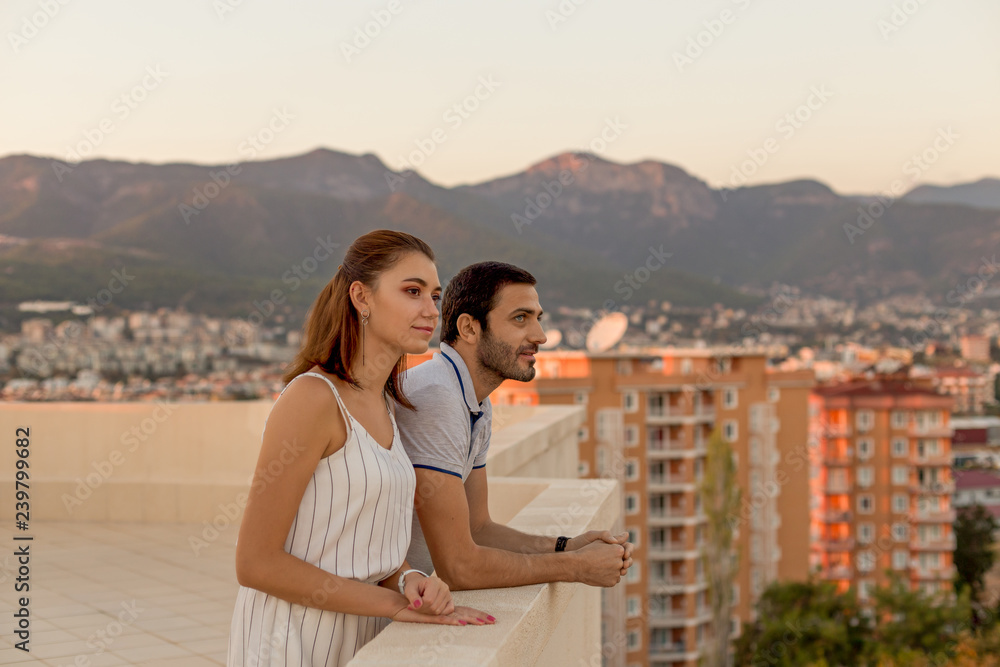 Young couple enjoying mountain and city view from rooftop terrac