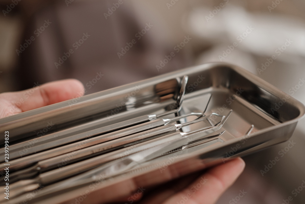 Dentist holding set steel tools - dental excavator, mirror and forceps in clinic. Dentistry, Orthodontics, Stomatology, Dental Care. Close up. selective focus Dentist holding set steel tools - dental excavator, mirror and forceps in clinic. Dentistry, Orthodontics, Stomatology, Dental Care. Close up. selective focus