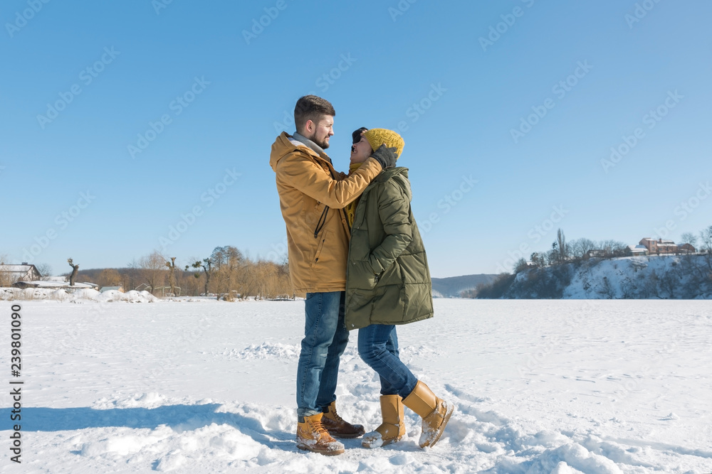 Happy young couple walking on winter sunny day. Full body, wide angle.