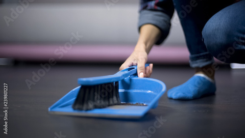 Migrant female worker dusting the floor with a brush, underpaid employment photo