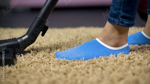 Female vacuuming rug to prevent allergy reaction, removing dirt from carpet