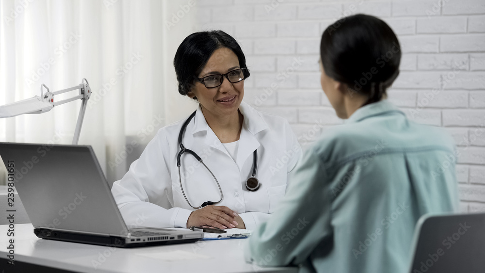 Friendly doctor talking to patient, promising to help, informing good results Friendly doctor talking to patient, promising to help, informing good results