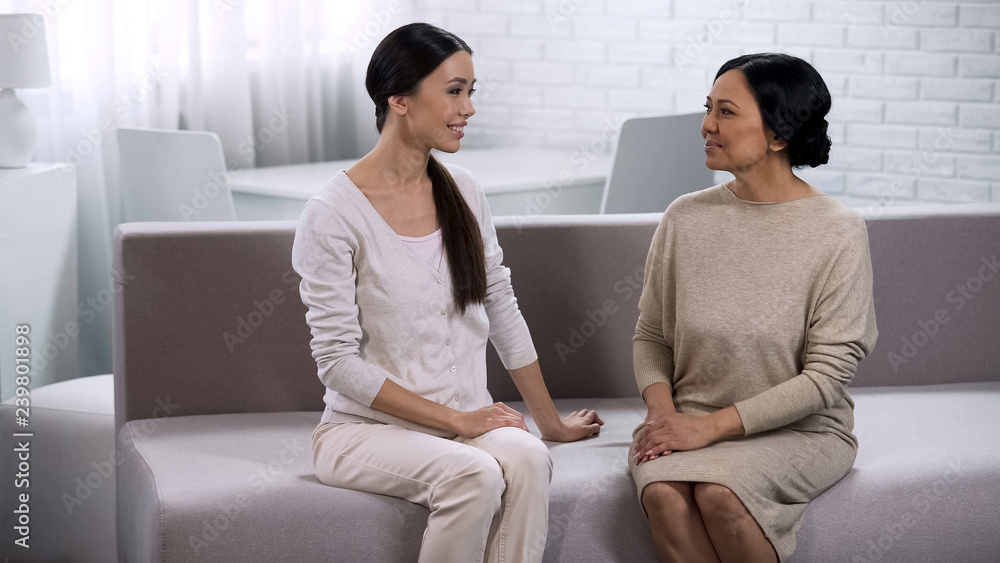 Two female friends communicating, sitting on couch, warm relations between women Two female friends communicating, sitting on couch, warm relations between women