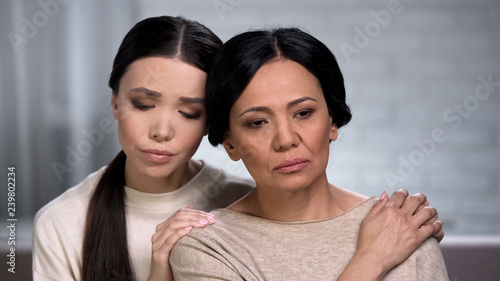 Foto Asian daughter supporting worried mother, problems with health, aging process