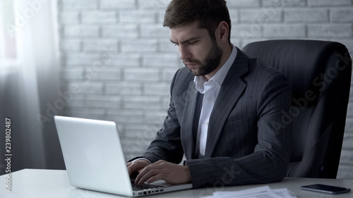 Canvas Print Businessman responding to email on laptop, pondering over forthcoming deal