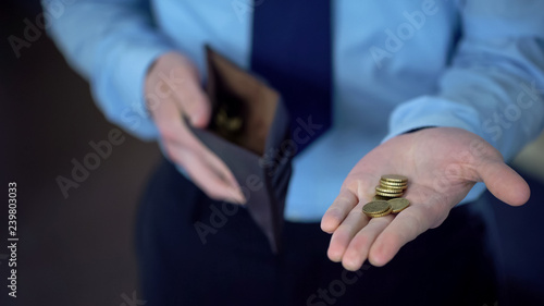 Man in suit holding coins in open palm, giving donations, low income, poverty