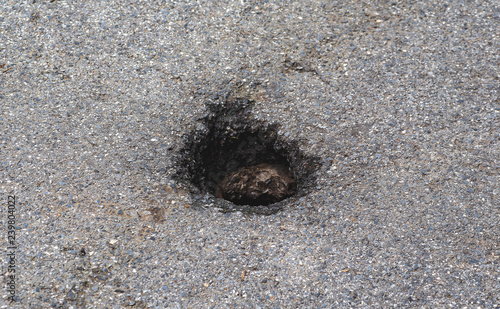 Deep hole damage on asphalt road 