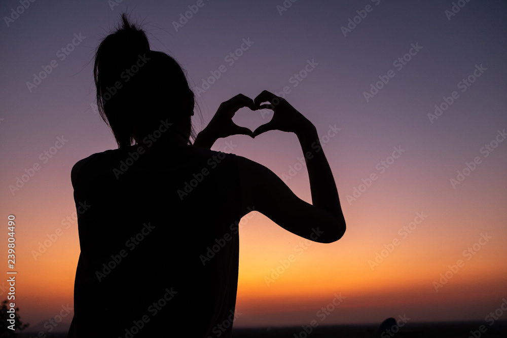 silhouette of young woman at sunset,heart shape