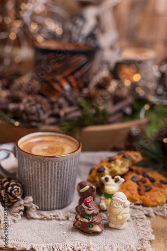 Fragrant coffee, chocolates in the form of Christmas figures. Cookies and hot drink for the holiday. Cozy atmosphere, candles decor. free space for text.