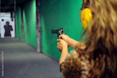 The girl shoots at the shooting range with a 45 caliber revolver