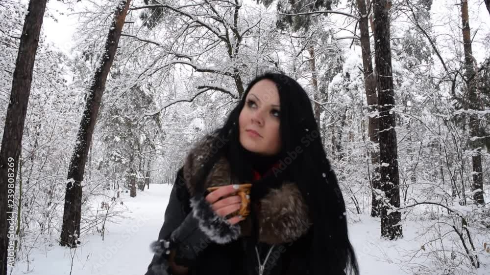 Young brunette girl drinking tea in winter forest. Young brunette girl drinking tea in winter forest.