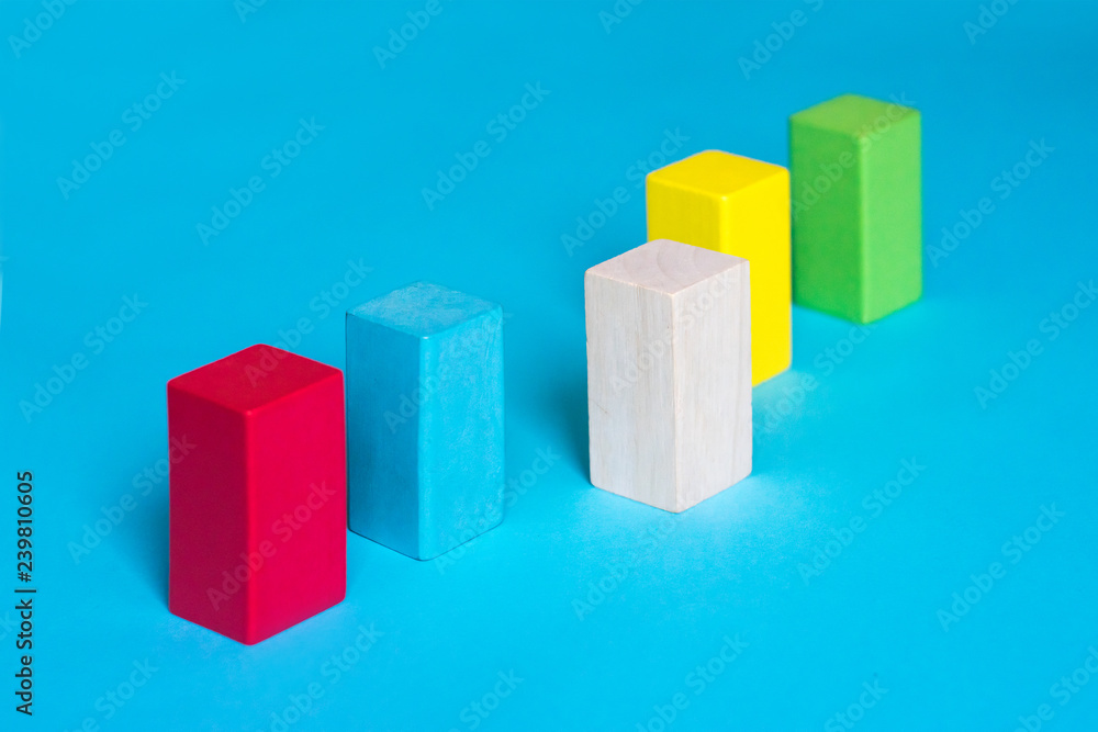 Many colored blocks in a row and one wooden block on blue background. Choice, difference, decision making, assortment concept Many colored blocks in a row and one wooden block on blue background. Choice, difference, decision making, assortment concept