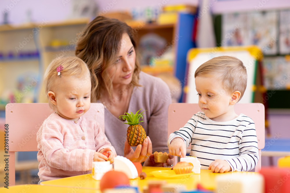 Preschool teacher with babies playing with colorful toys at kindergarten Preschool teacher with babies playing with colorful toys at kindergarten