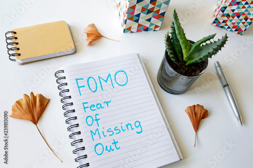 FOMO fear of missing out written in a notebook on white table