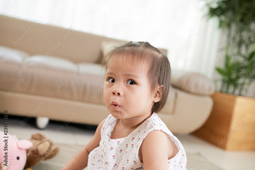 Adorable curious little Vetnamese girl playing on the floor in living room Adorable curious little Vetnamese girl playing on the floor in living room
