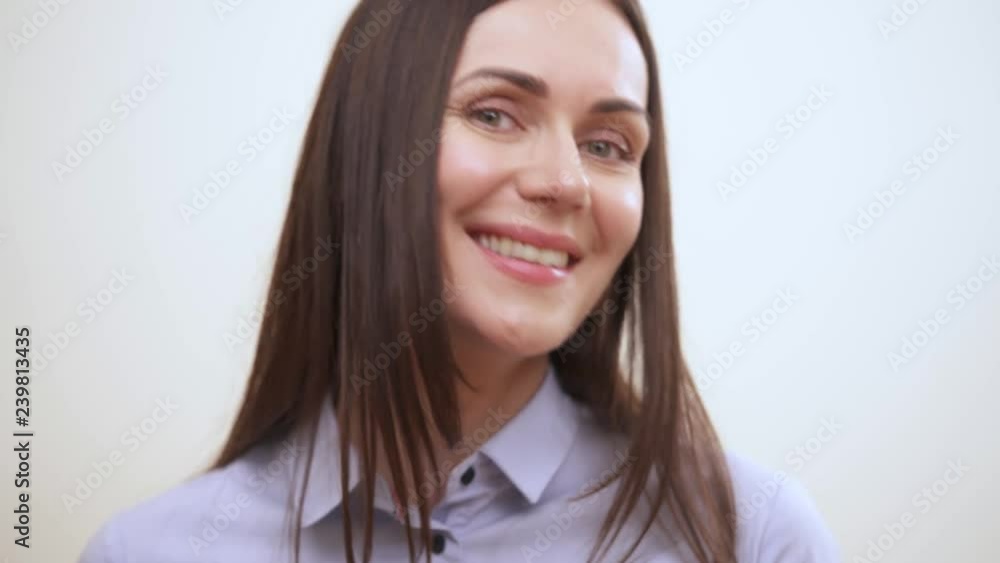 A portrait of a pretty long-haired brunette smiling and looking into the camera A portrait of a pretty long-haired brunette smiling and looking into the camera