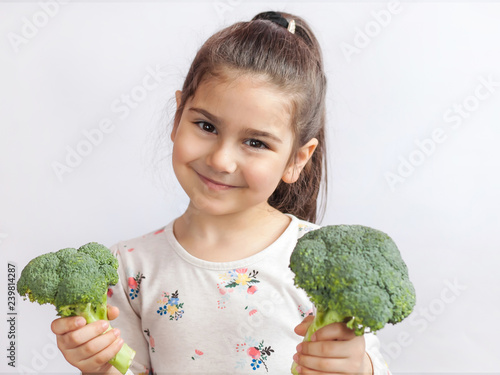 Happy smiling child girl eating vegetables. Healthy food. Fresh broccoli.
