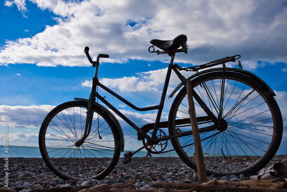 Classic (old) bicycle by the sea, blue sky with clouds, contrasting silhouette of a bicycle Classic (old) bicycle by the sea, blue sky with clouds, contrasting silhouette of a bicycle