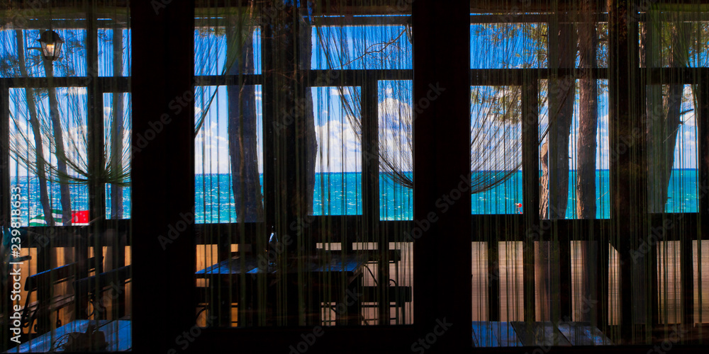 Through the window you can see the cafe's atmosphere and the blue and turquoise sea and sky. Through the window you can see the cafe's atmosphere and the blue and turquoise sea and sky.