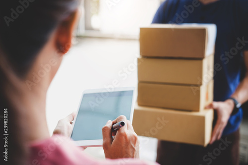 Woman customer appending signature in digital tablet and receiving a cardboard boxes parcel from delivery service courier, Home delivery service and working with service mind