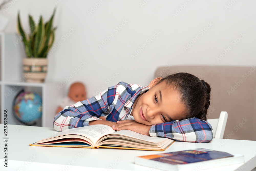 Studio shot of beautiful little girl of with braids of frizzy. She laid her head on the book and smiling dreams of something Studio shot of beautiful little girl of with braids of frizzy. She laid her head on the book and smiling dreams of something