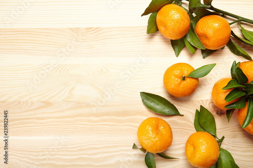 Fresh ripe tangerines wth leaves on wooden background with copy space. photo