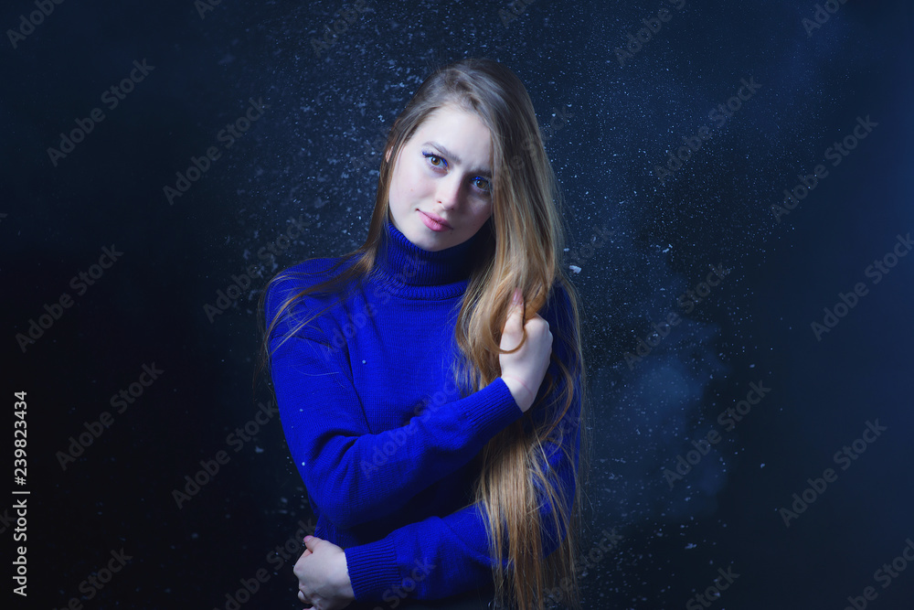 Beautiful, young girl with blond hair in a blue sweater on a snowfall in winter Beautiful, young girl with blond hair in a blue sweater on a snowfall in winter