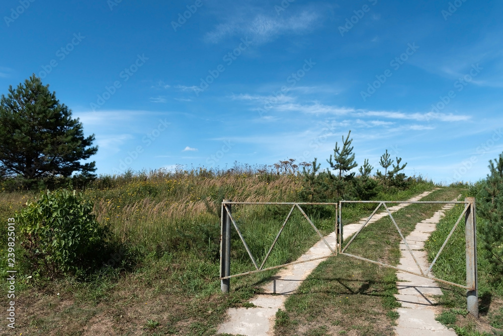 The concept of finding your life path. Opening up new features. The road to the horizon, closed gates, no fence.