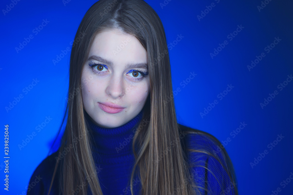Beautiful, young girl with blond hair in a blue sweater on a snowfall in winter Beautiful, young girl with blond hair in a blue sweater on a snowfall in winter