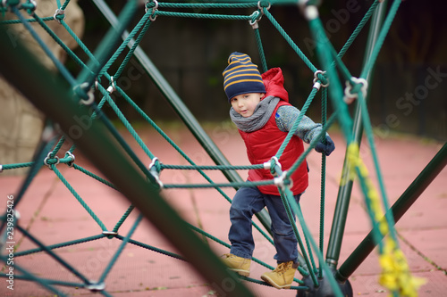 Little boy playing on modern kids play ground.