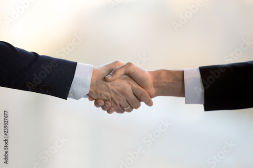 Close up two businessmen in suits shake hands greeting each other. Executive manager and client after successful negotiations handshaking. Boss congratulate new company employee is glad to cooperate