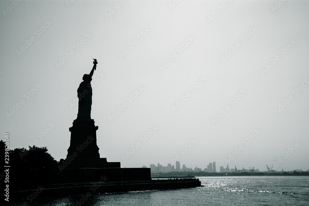 Liberty statue in New York City with skyline of the island of Manhattan