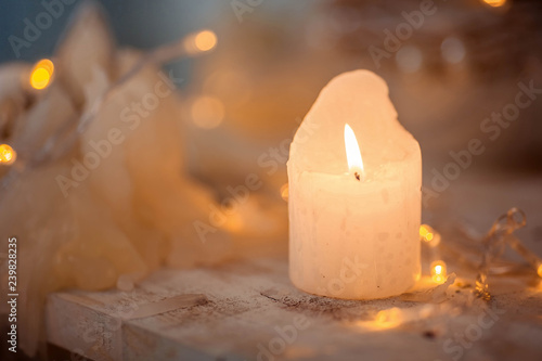 Burning candle on a wooden surface, against the background of Christmas lights. Christmas concept.