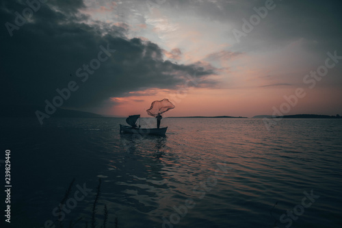A fisherman tries to catch fish in sunset © toghrul