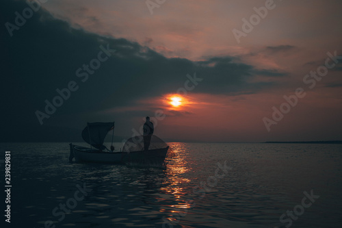Fisherman collects fish in sunset