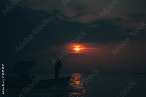 Fisherman collects fish in sunset